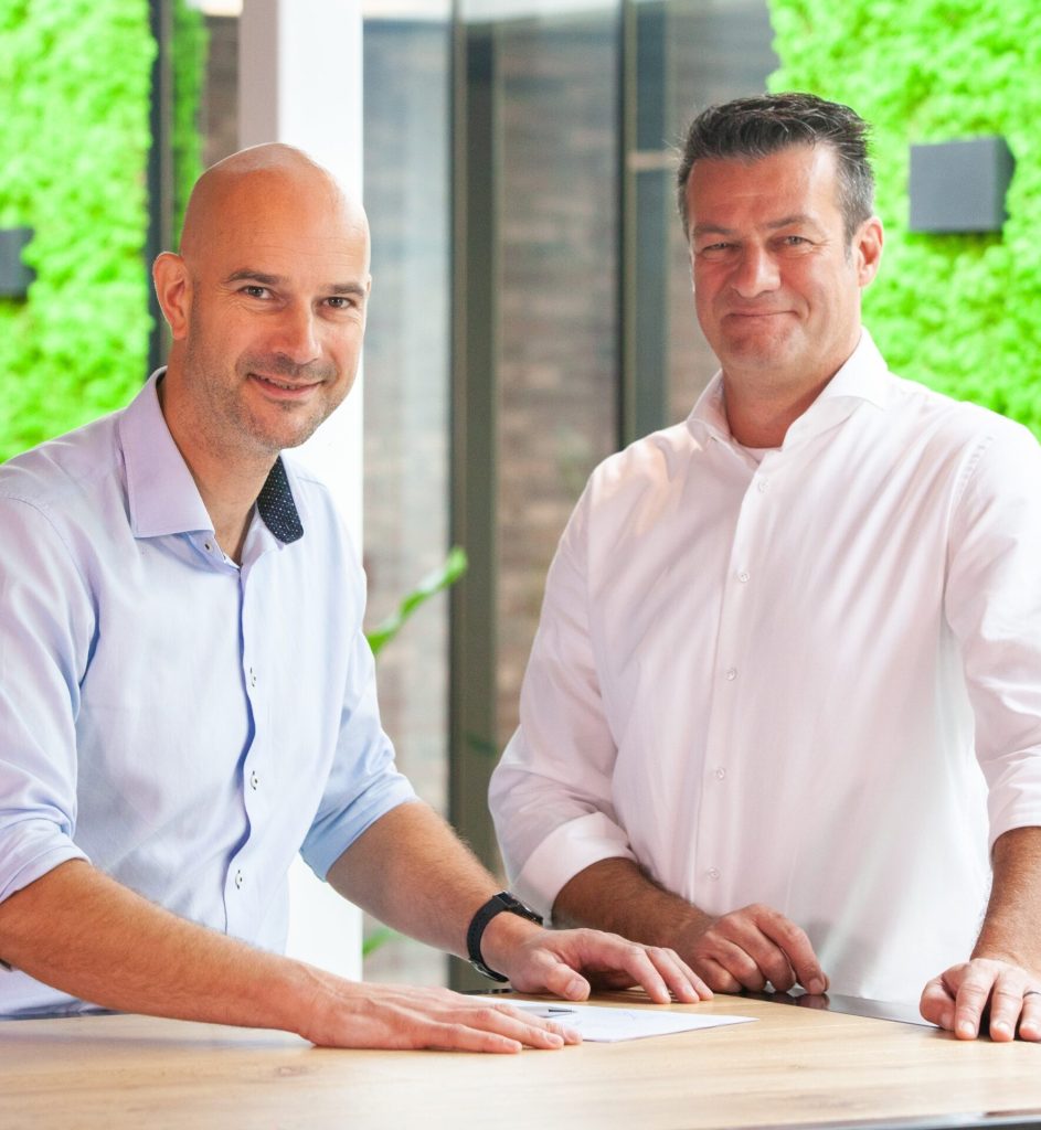 Twee mannen in witte overhemden aan tafel.