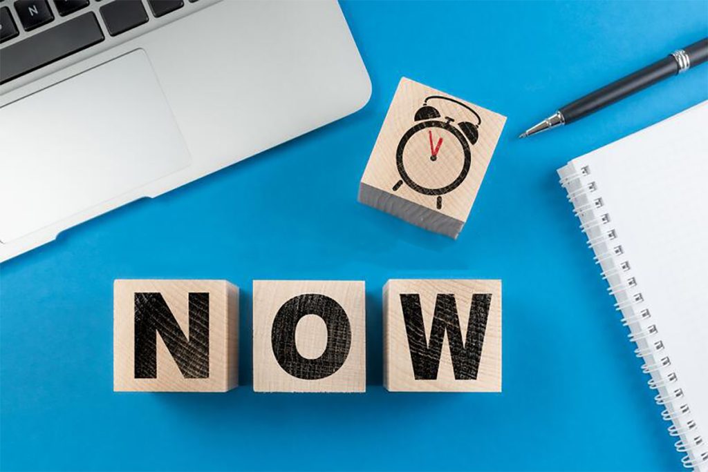 Houten blokken spellen 'NOW' met klok.