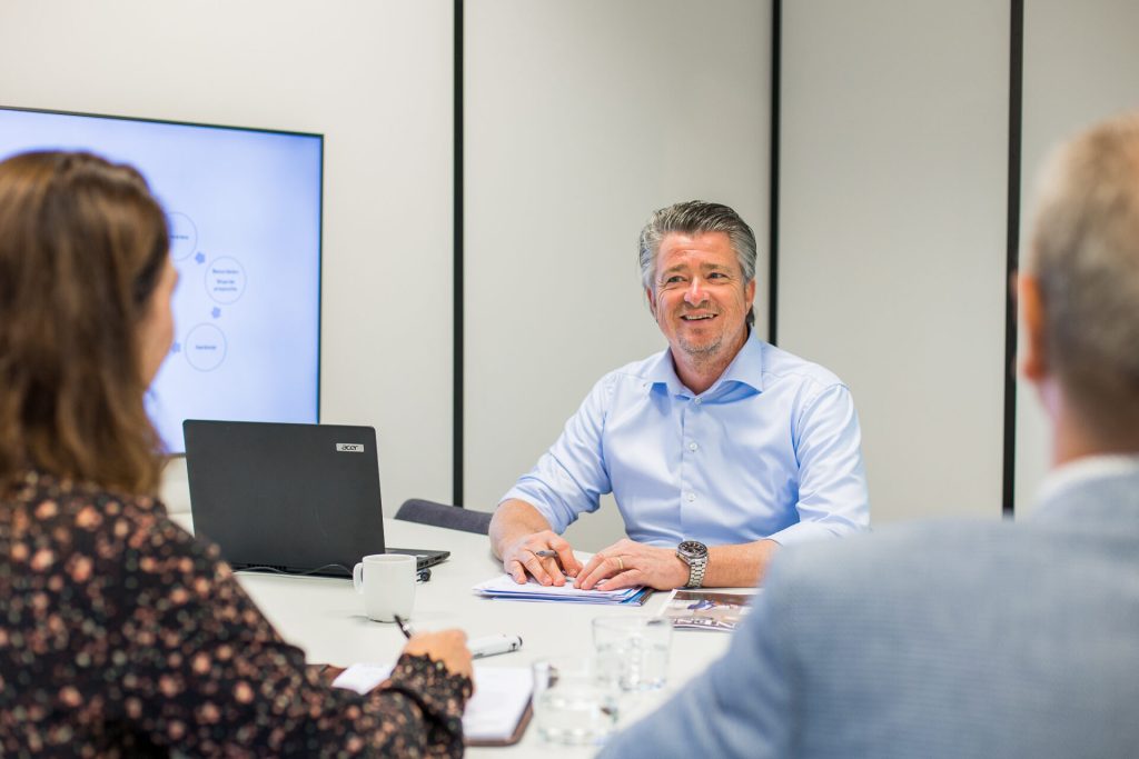 Vergadering met laptop en notities op kantoor.