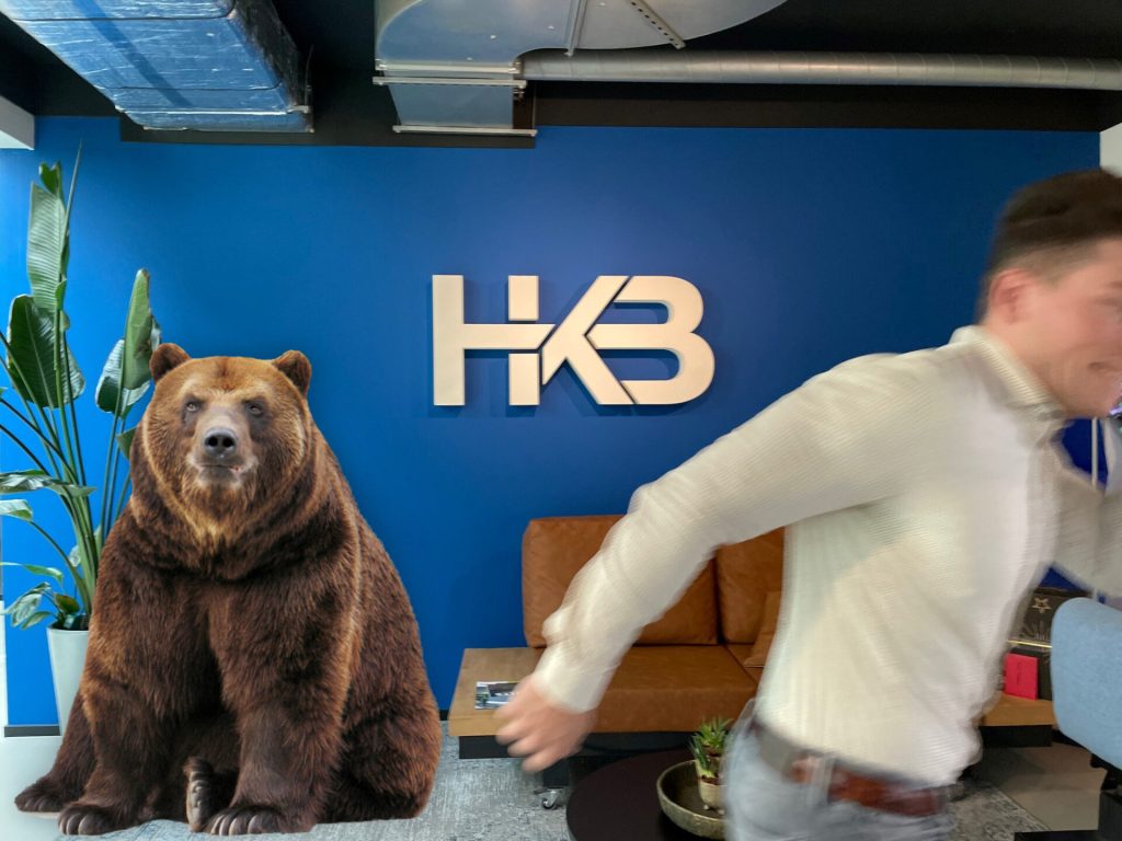 Man rent weg voor beer in kantoor met HKB logo.