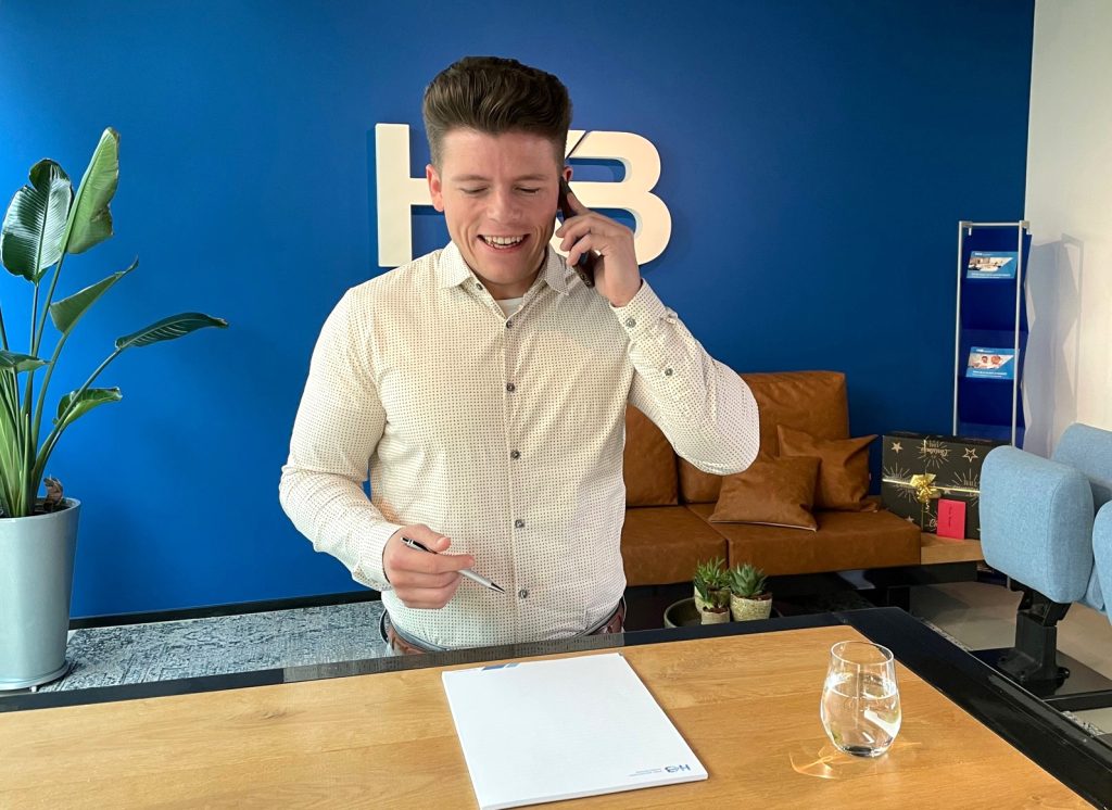 Man aan telefoon met notitieblok op balie.