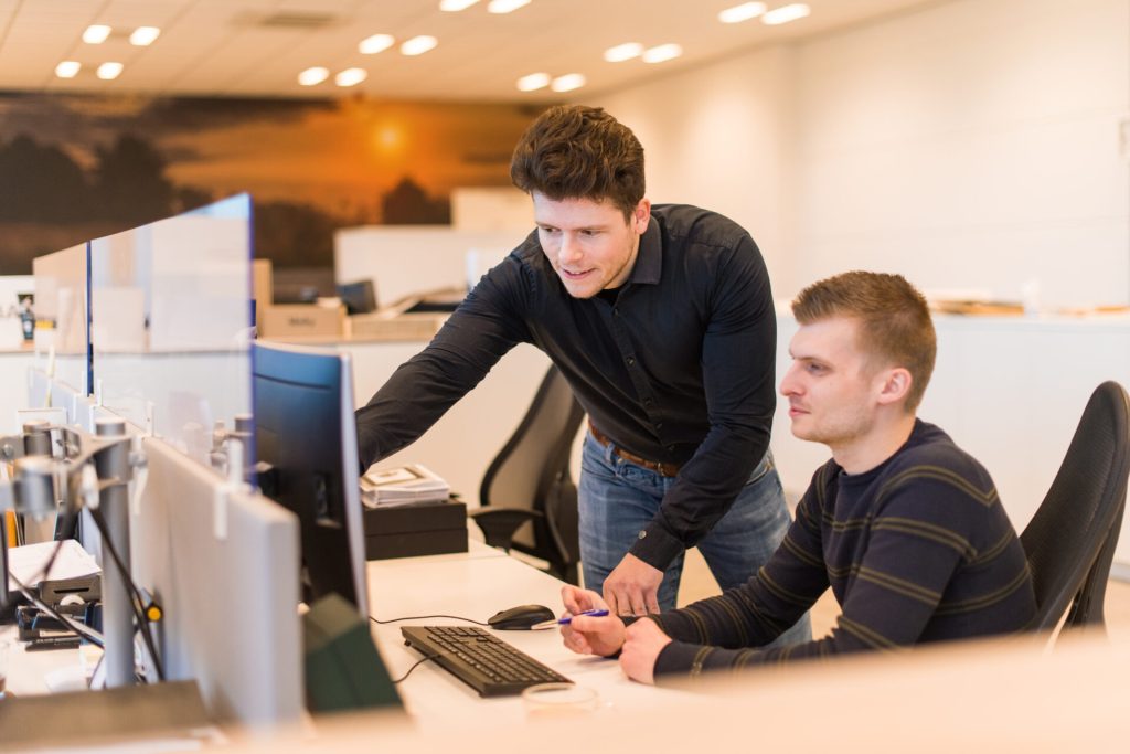 Twee mannen werken samen aan bureaucomputer