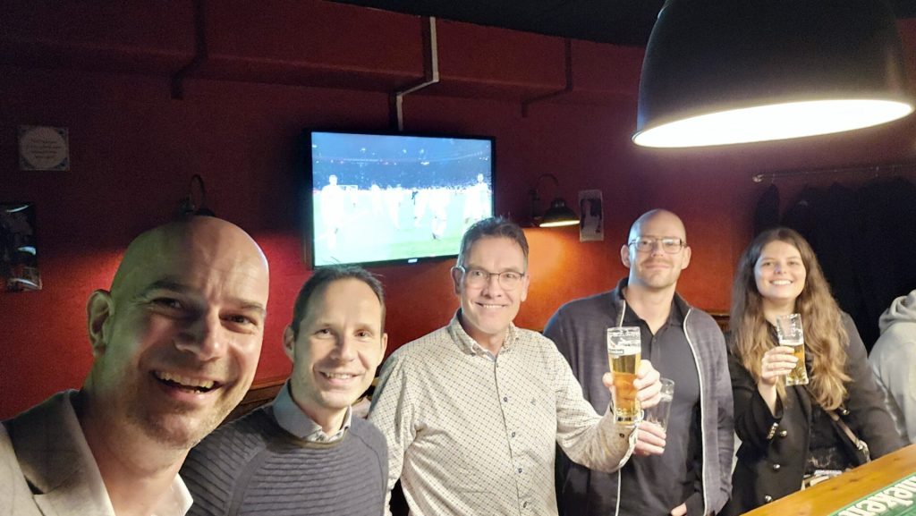 Groep vrienden met bier in gezellige bar.