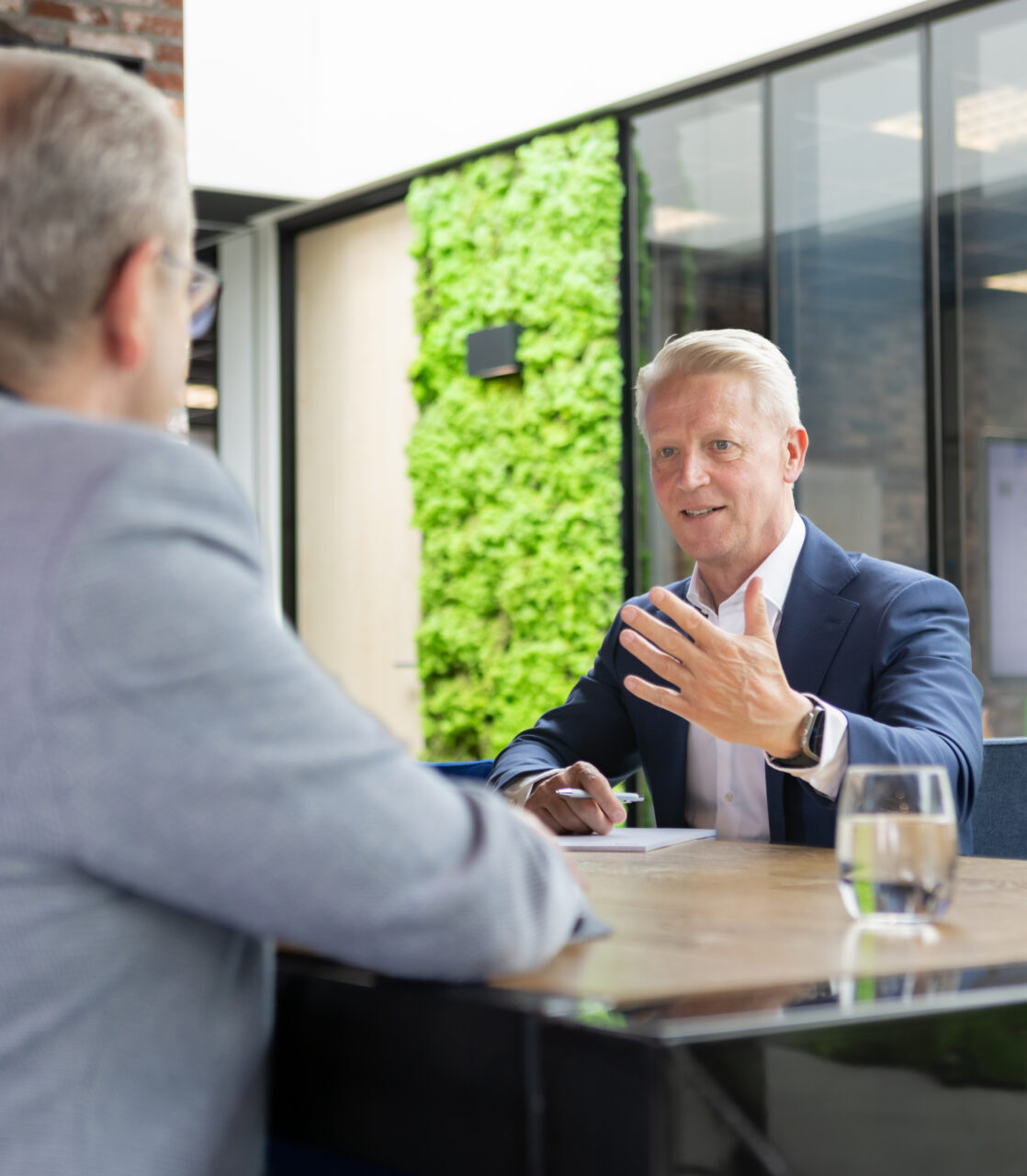 Twee mannen in gesprek aan kantoor tafel.