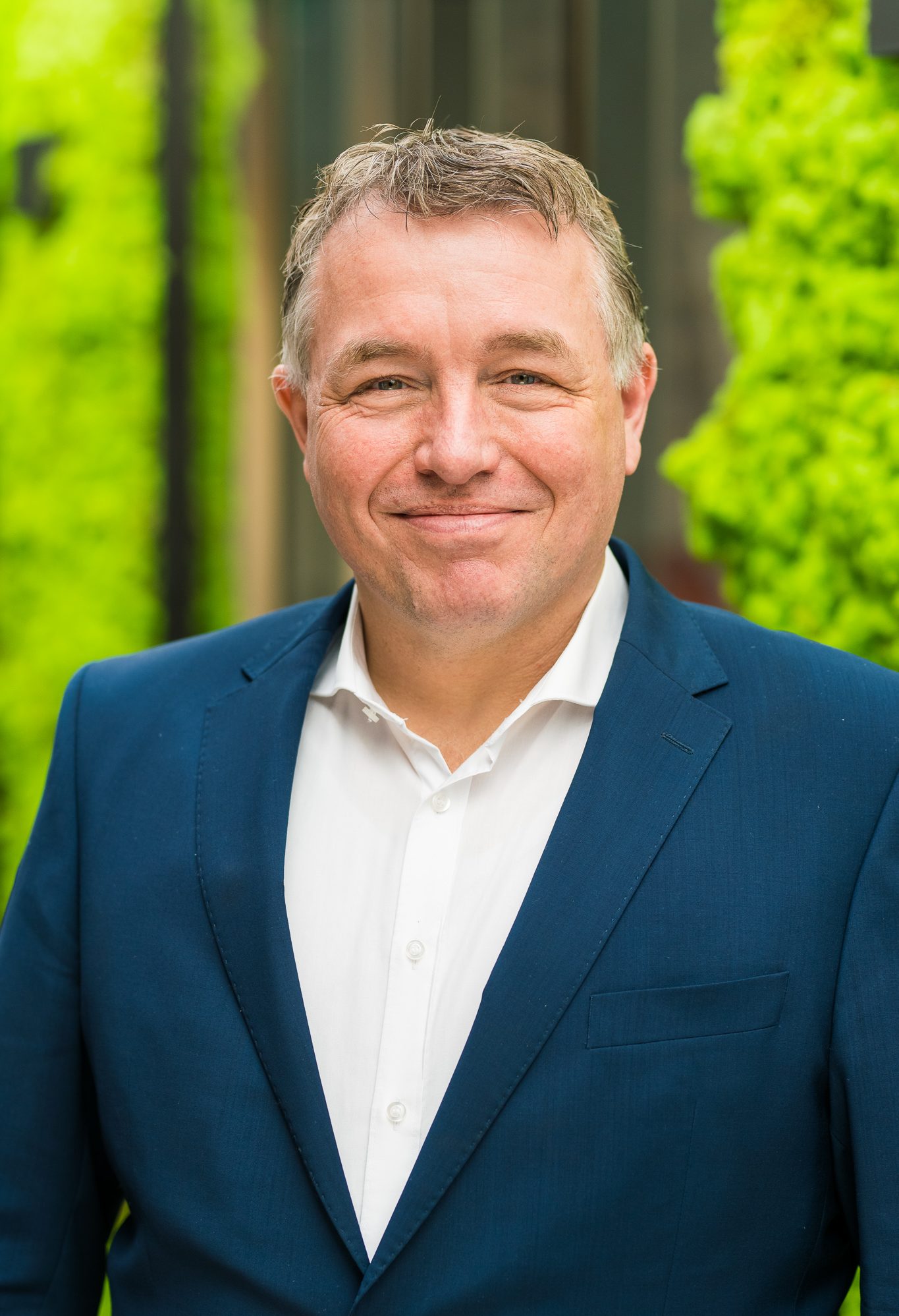 Man in blauwe blazer met groene achtergrond