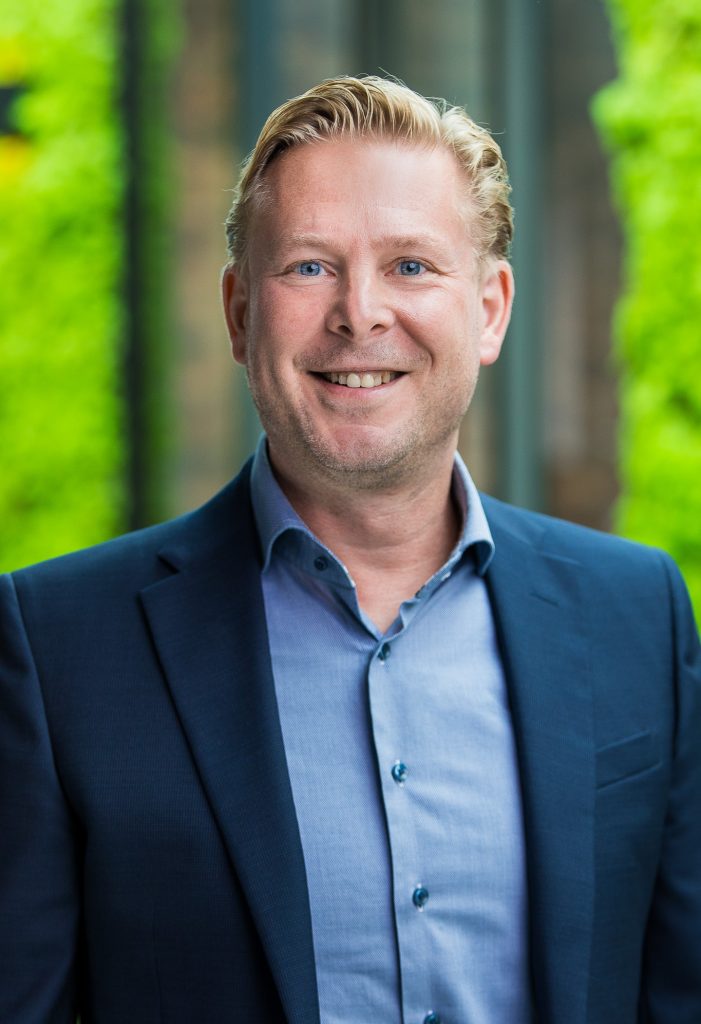 Man in blauwe blazer glimlacht naar camera