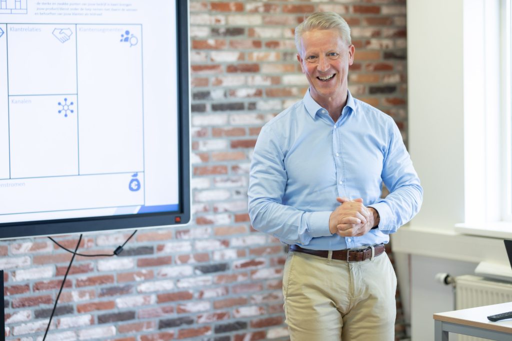 Man presenteert bij scherm met bedrijfsdiagram.