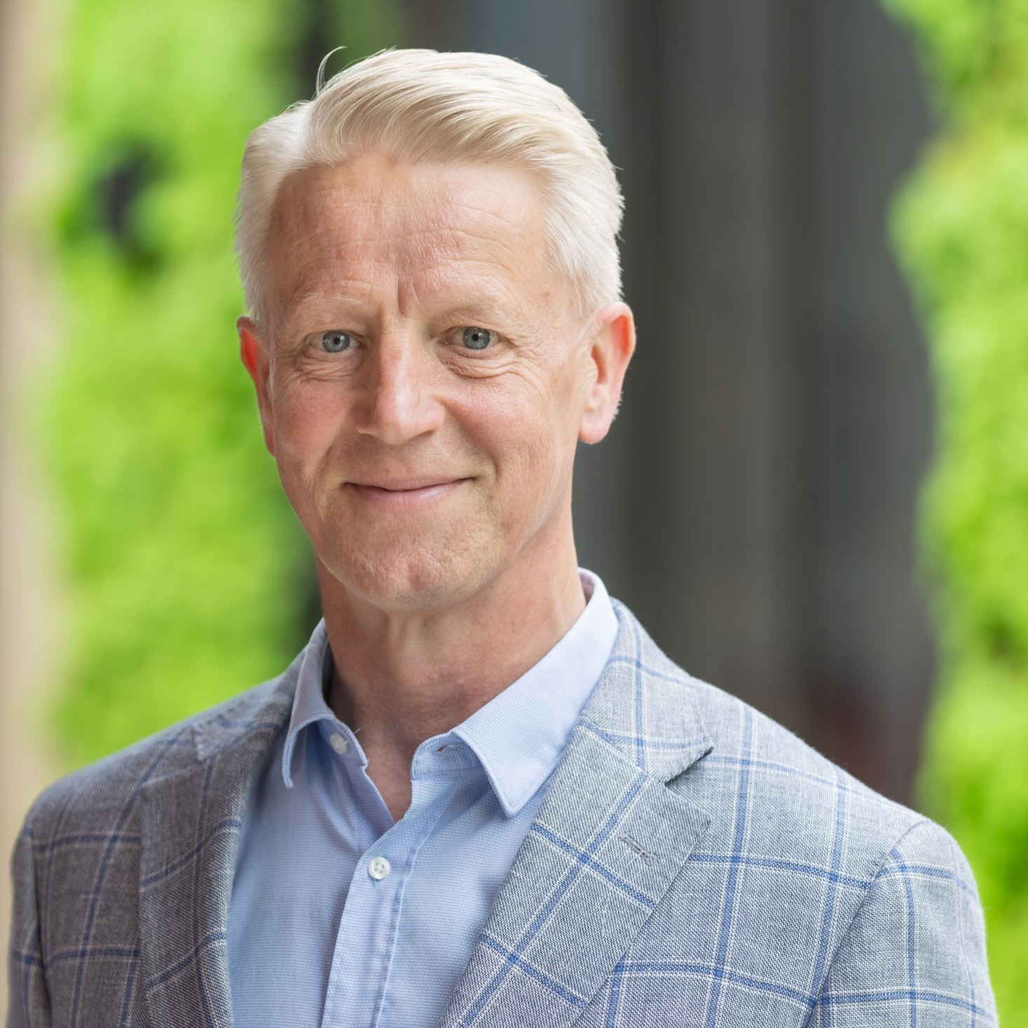 Man in blauw pak en blond haar glimlacht.