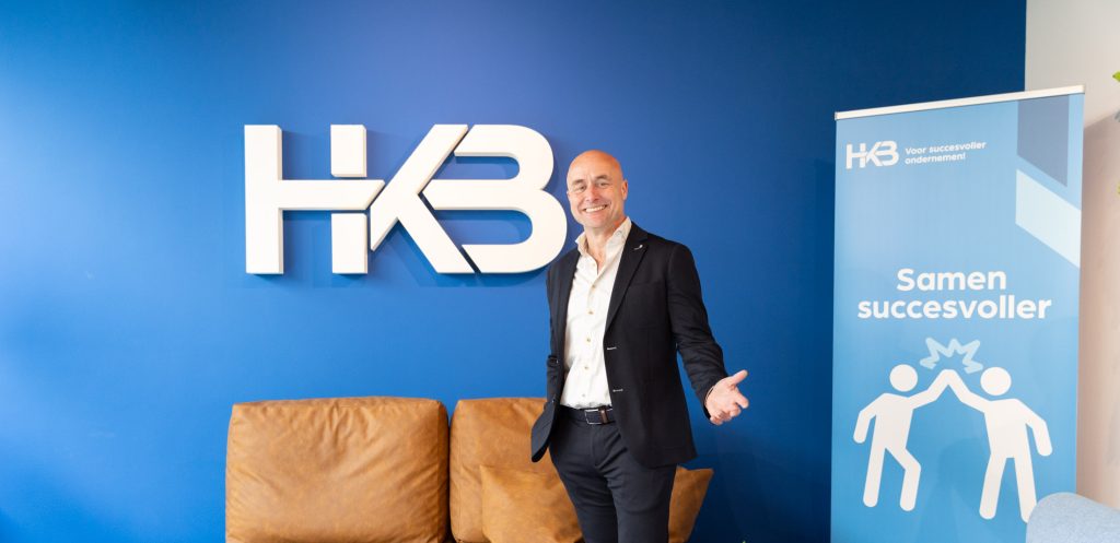 Man bij HKB kantoor entree met banner.