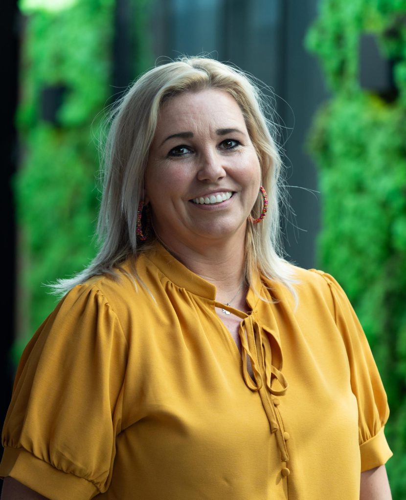 Vrouw in gele blouse met groene achtergrond.