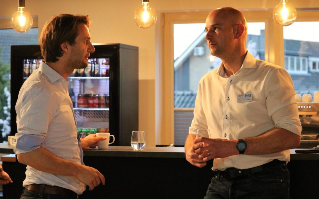 Twee mannen praten informeel bij een bar.