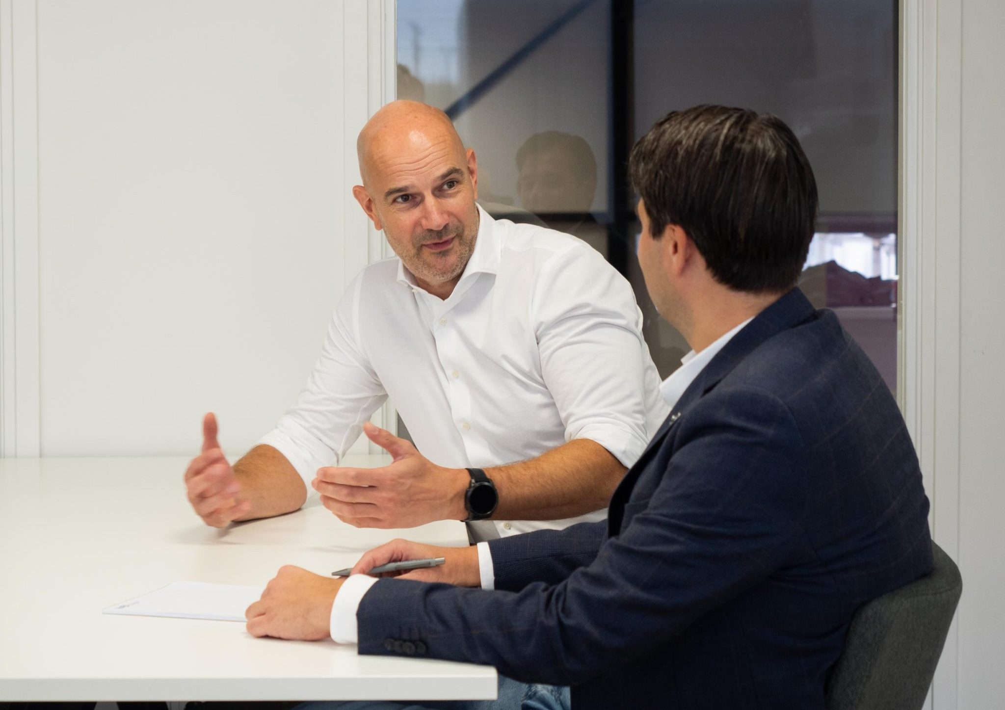 Mannen in overleg aan vergadertafel.