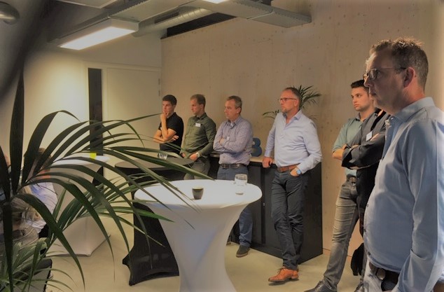 Mensen luisteren naar presentatie in moderne kantoorruimte.