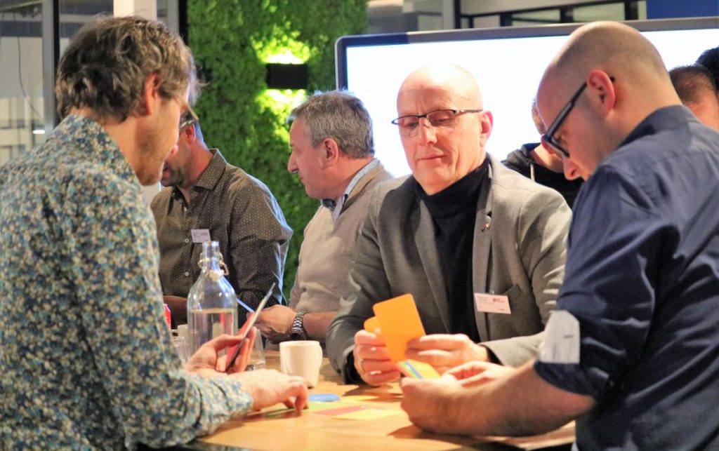 Mensen aan tafel met kleurrijke kaarten.