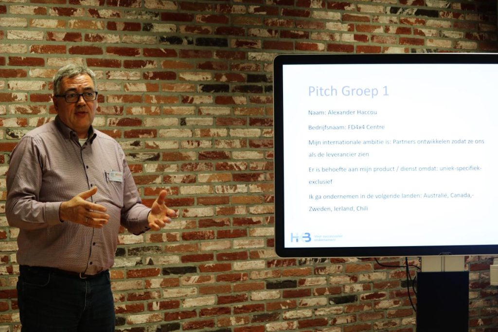 Man presenteert pitch voor groep met scherm.