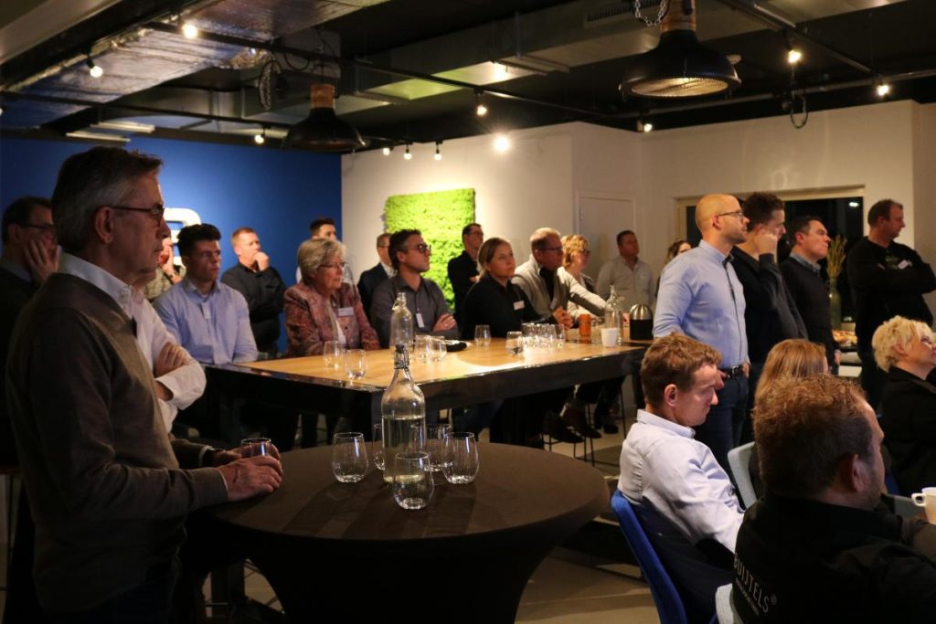 Mensen luisteren aandachtig tijdens een presentatie in een zaal.