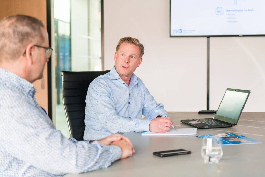 Twee mannen in vergadering met laptop en notities