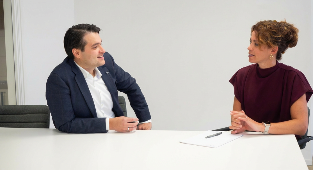 Twee mensen in gesprek aan een witte tafel.