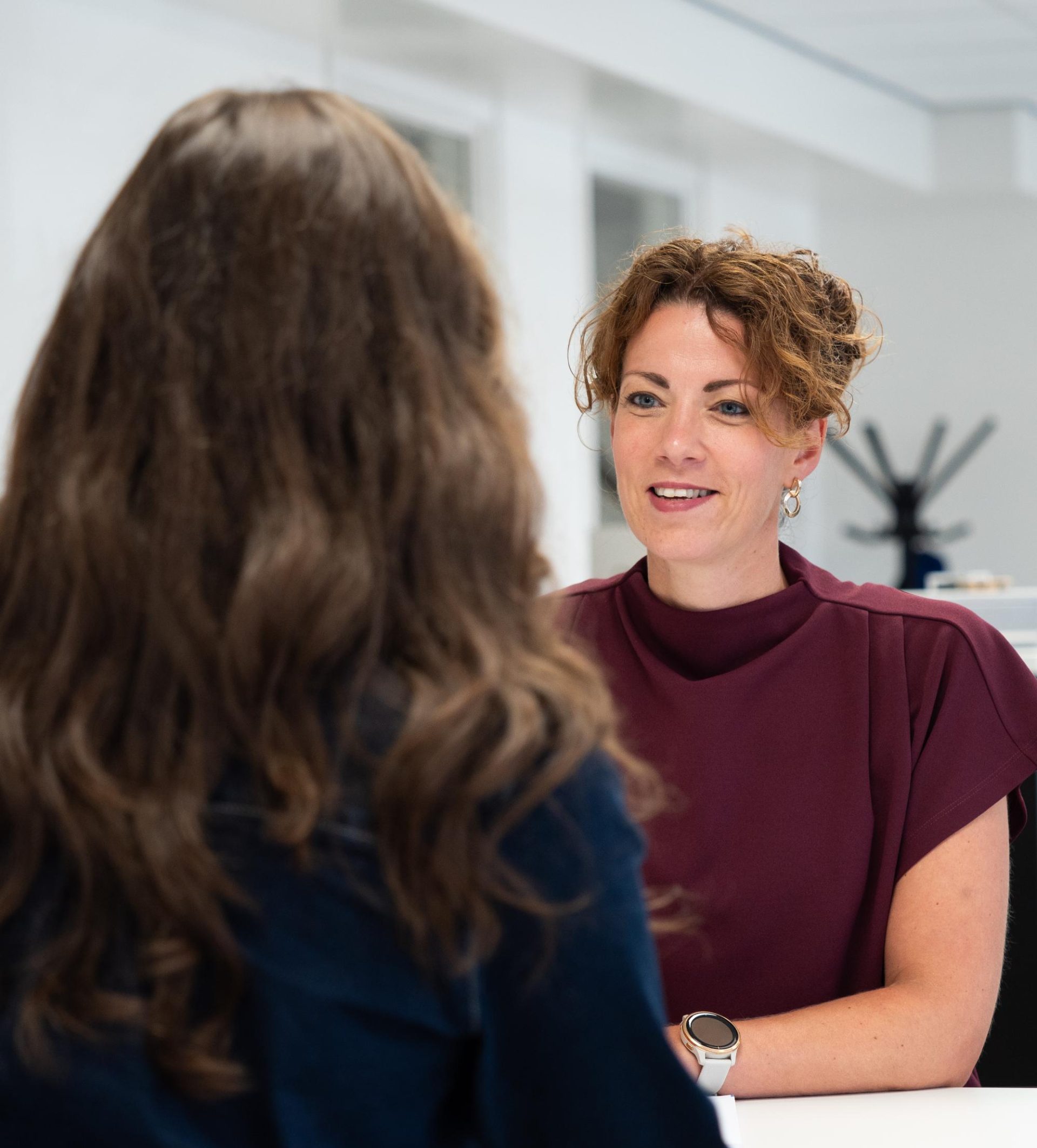 Twee vrouwen in gesprek aan tafel.
