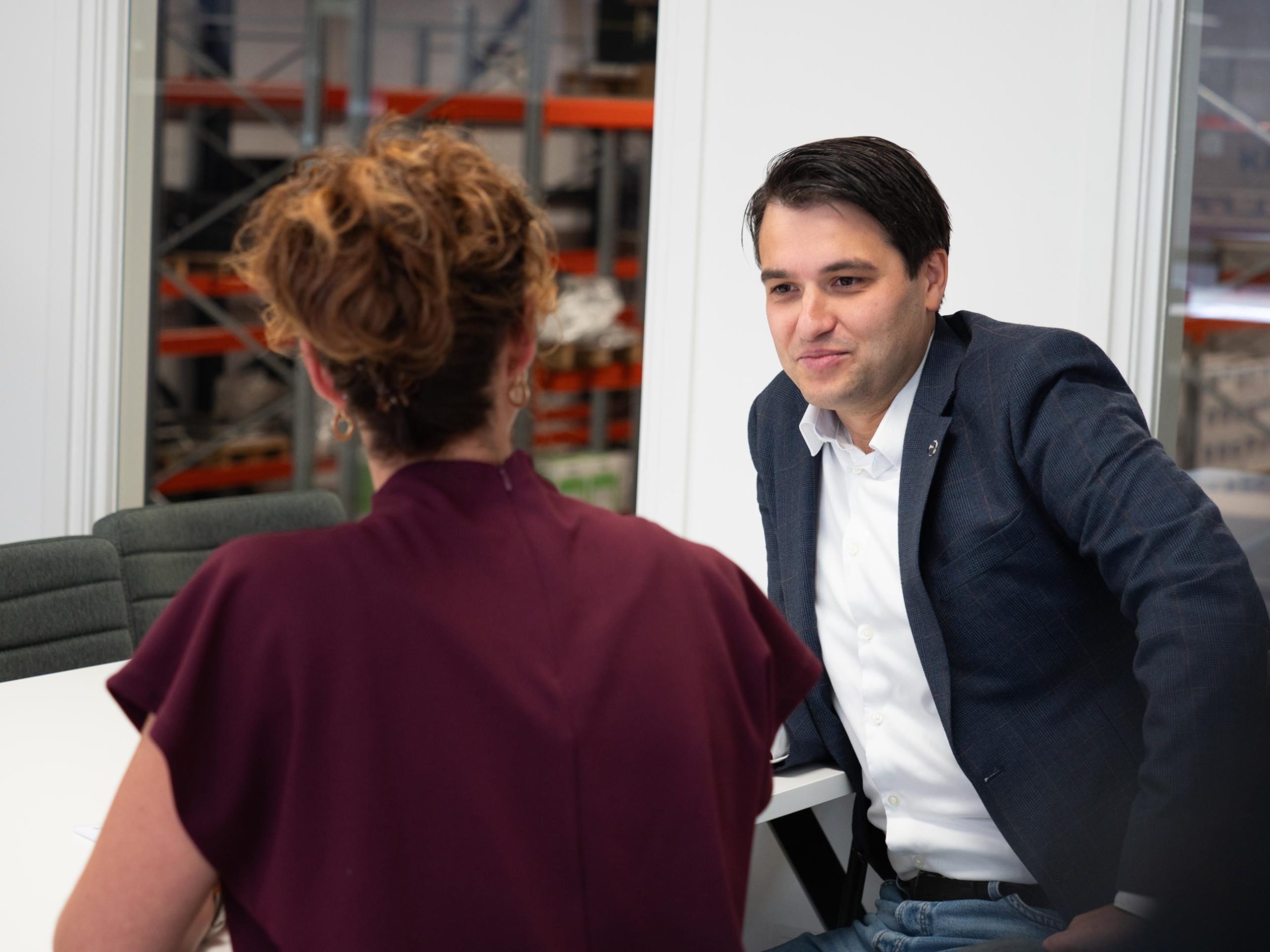 Twee mensen in gesprek aan tafel op kantoor.