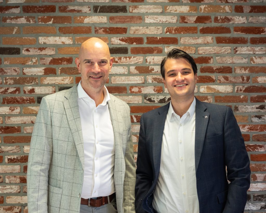 Twee mannen in pakken voor een bakstenen muur.