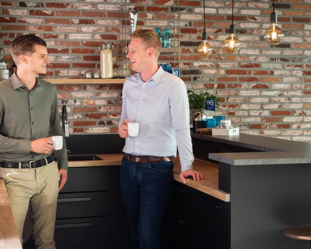 Twee mannen praten met koffie in keuken
