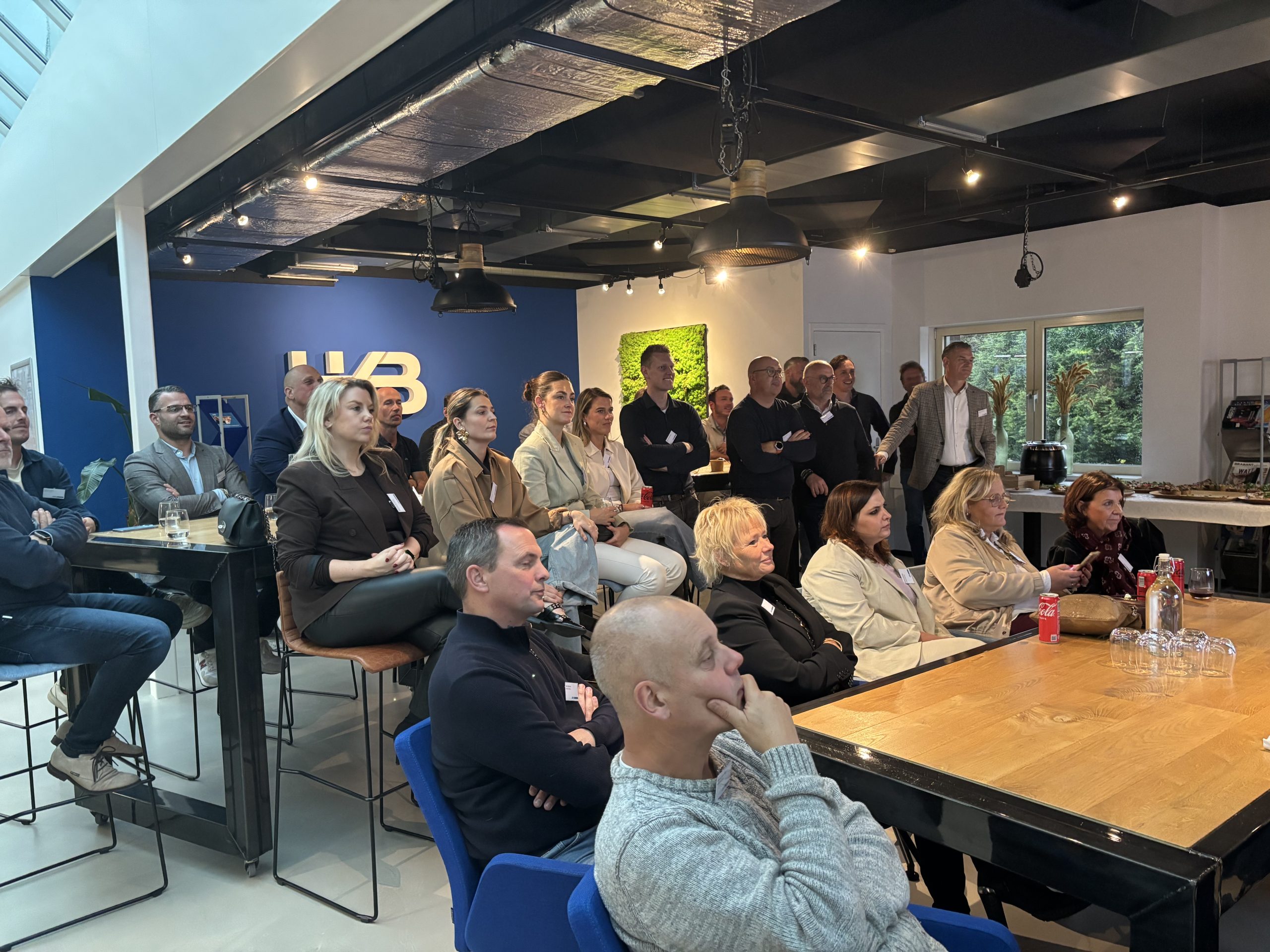 Mensen kijken naar presentatie in moderne vergaderruimte.