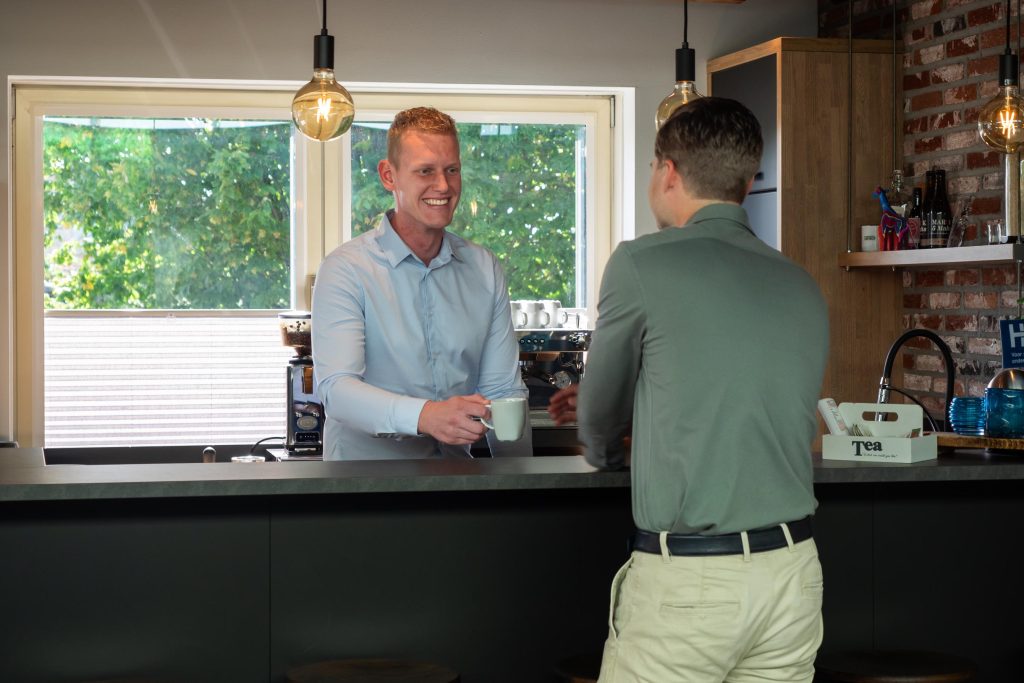 Barman serveert koffie aan klant in café.